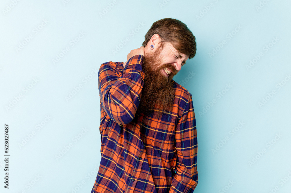 Young caucasian red-haired man isolated on blue background suffering neck pain due to sedentary lifestyle. Young caucasian red-haired man isolated on blue background suffering neck pain due to sedentary lifestyle.