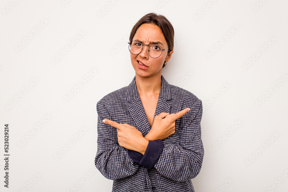 Young hispanic woman isolated on white background points sideways, is trying to choose between two options. Young hispanic woman isolated on white background points sideways, is trying to choose between two options.