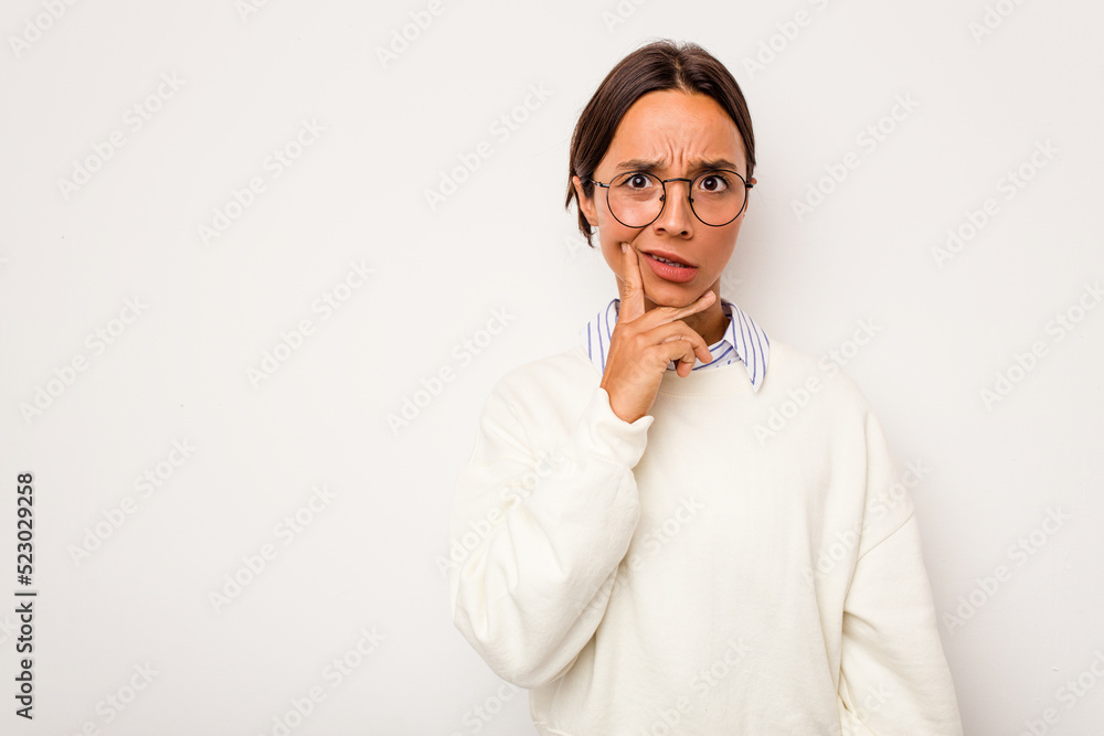Young hispanic woman isolated on white background looking sideways with doubtful and skeptical expression.