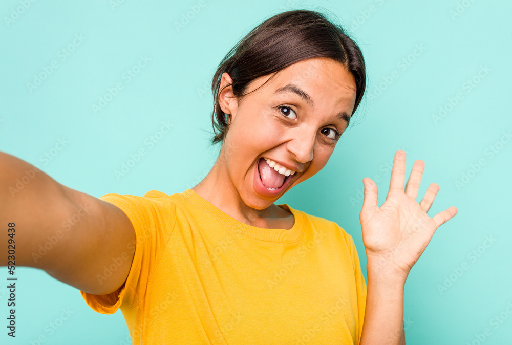 Young hispanic woman doing a selfie isolated on blue background Young hispanic woman doing a selfie isolated on blue background