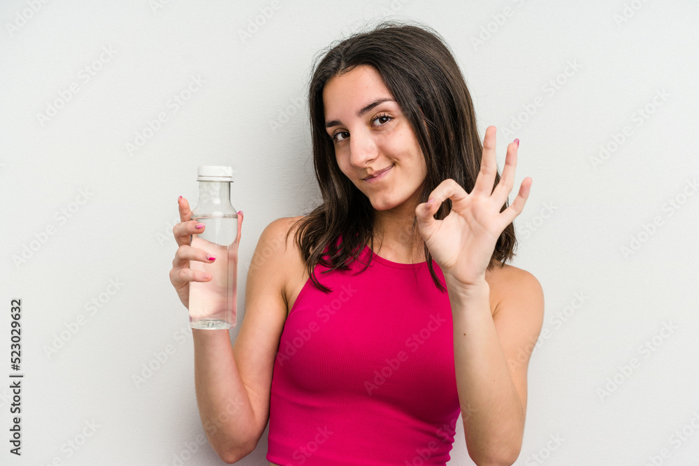 Young caucasian woman holding a bottle of water isolated on white background cheerful and confident showing ok gesture. Young caucasian woman holding a bottle of water isolated on white background cheerful and confident showing ok gesture.