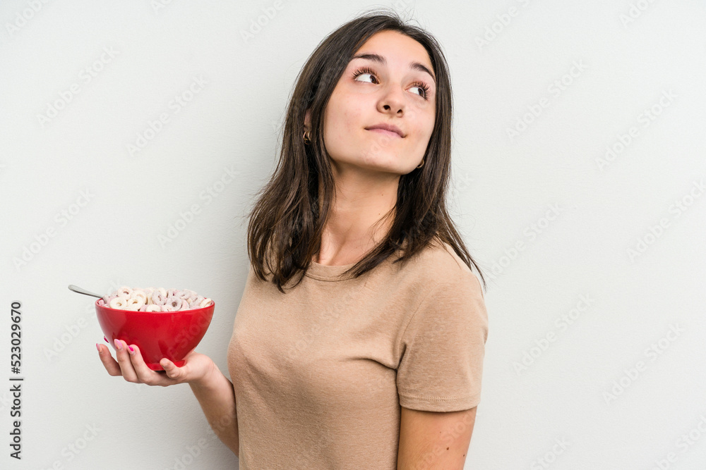 Young caucasian woman holding bowl of cereals isolated on white background looks aside smiling, cheerful and pleasant. Young caucasian woman holding bowl of cereals isolated on white background looks aside smiling, cheerful and pleasant.