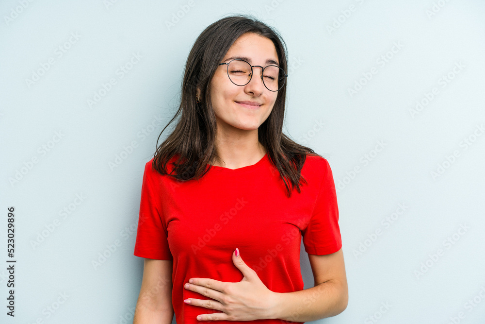 Young caucasian woman isolated on blue background touches tummy, smiles gently, eating and satisfaction concept. Young caucasian woman isolated on blue background touches tummy, smiles gently, eating and satisfaction concept.