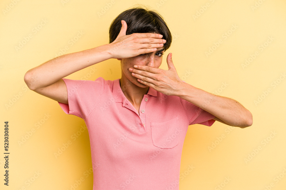 Young caucasian woman with a short hair cut isolated blink at the camera through fingers, embarrassed covering face. Young caucasian woman with a short hair cut isolated blink at the camera through fingers, embarrassed covering face.
