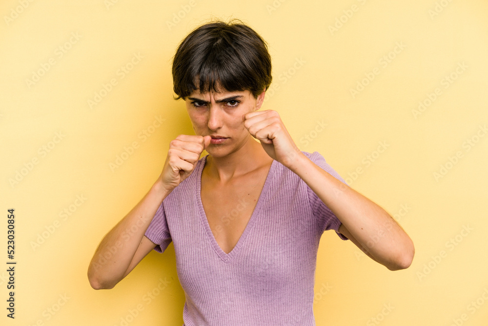 Young caucasian woman with a short hair cut isolated throwing a punch, anger, fighting due to an argument, boxing.