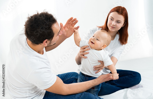mom and dad sit on the floor and play with the baby. a happy family. family in studio or at home