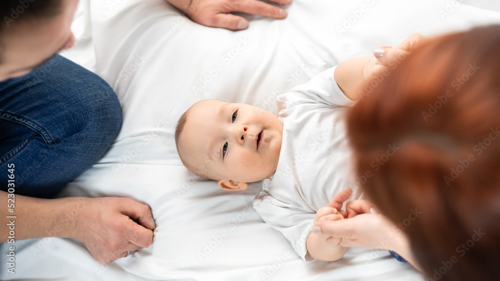 mom and dad sit on the floor and play with the baby. a happy family. family in studio or at home mom and dad sit on the floor and play with the baby. a happy family. family in studio or at home