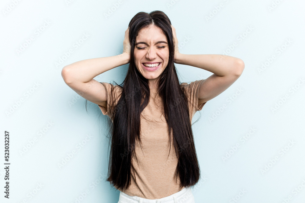 Young caucasian woman isolated on blue background covering ears with hands. Young caucasian woman isolated on blue background covering ears with hands.