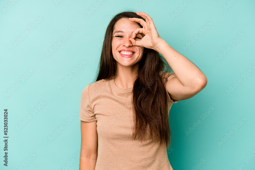 Young caucasian woman isolated on blue background excited keeping ok gesture on eye. Young caucasian woman isolated on blue background excited keeping ok gesture on eye.