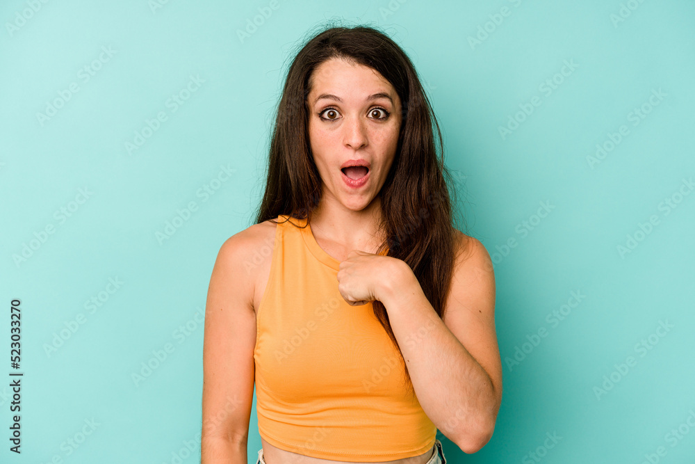 Young caucasian woman isolated on blue background surprised pointing with finger, smiling broadly. Young caucasian woman isolated on blue background surprised pointing with finger, smiling broadly.