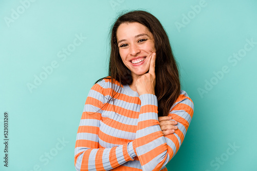 Young caucasian woman isolated on blue background smiling happy and confident, touching chin with hand.