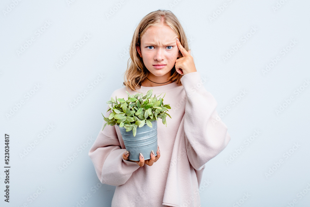 Caucasian teen girl holding a plant isolated on blue background showing a disappointment gesture with forefinger. Caucasian teen girl holding a plant isolated on blue background showing a disappointment gesture with forefinger.