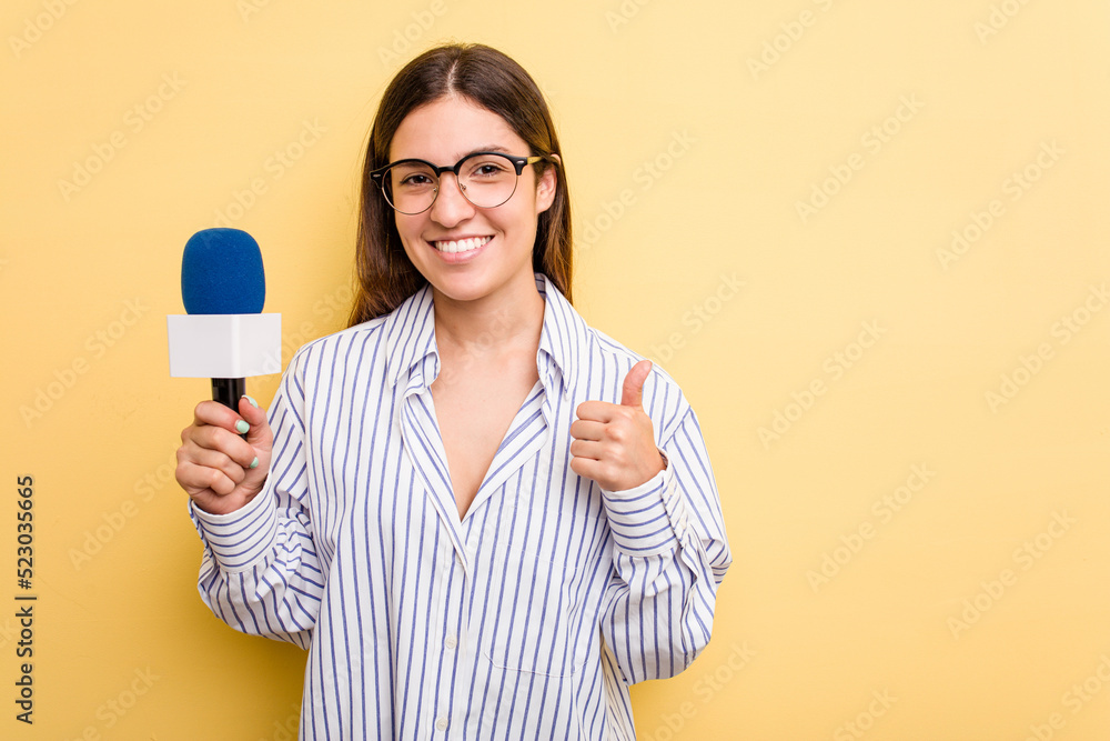 Young caucasian presenter TV woman isolated on yellow background smiling and raising thumb up Young caucasian presenter TV woman isolated on yellow background smiling and raising thumb up