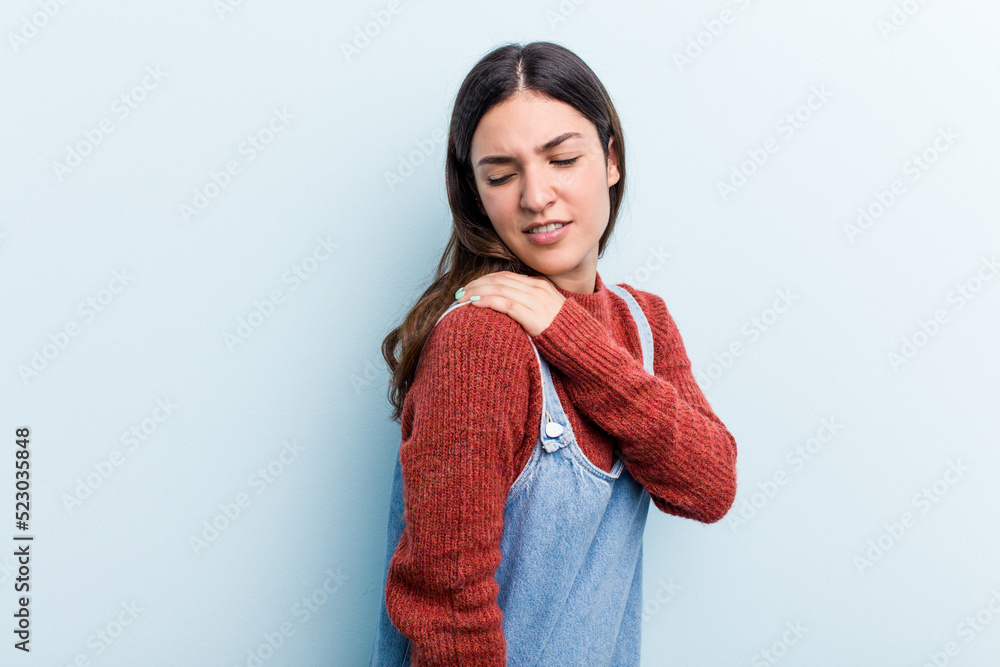 Young caucasian woman isolated on blue background having a shoulder pain. Young caucasian woman isolated on blue background having a shoulder pain.