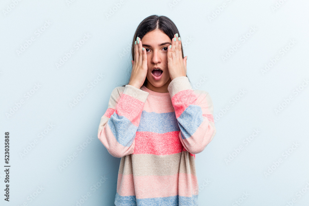 Young caucasian woman isolated on blue background having fun covering half of face with palm. Young caucasian woman isolated on blue background having fun covering half of face with palm.