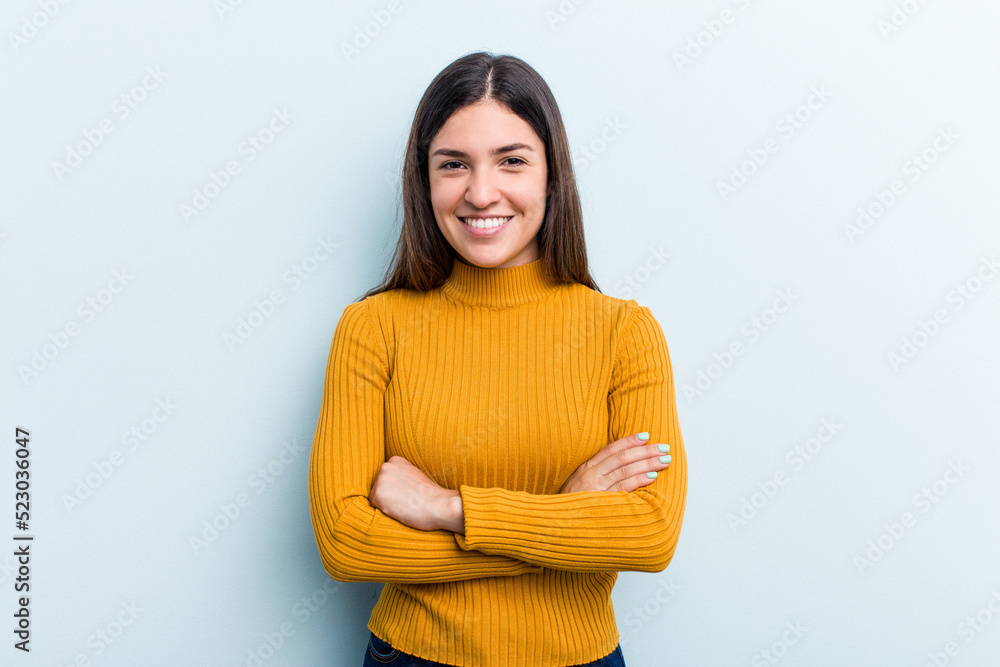 Young caucasian woman isolated on blue background who feels confident, crossing arms with determination. Young caucasian woman isolated on blue background who feels confident, crossing arms with determination.