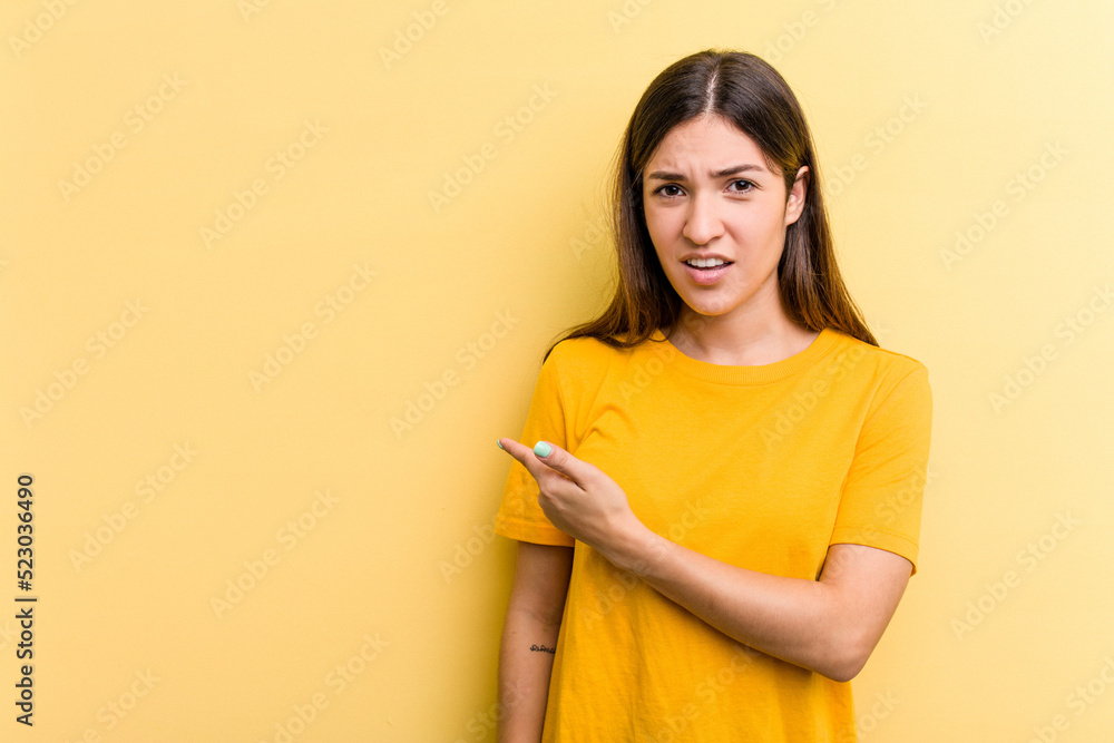 Obraz premium Young caucasian woman isolated on yellow background pointing to the side