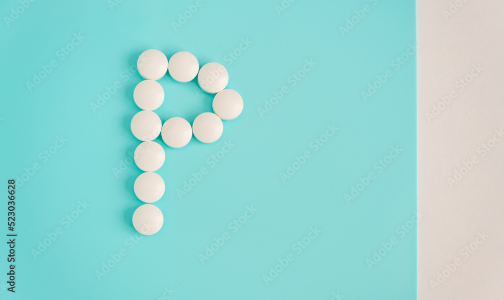 Letter P made from white pills on a blue background. White medical pills. Macro top view with copy space. Health care and pills concept, pharmaceutical, disease prevention Letter P made from white pills on a blue background. White medical pills. Macro top view with copy space. Health care and pills concept, pharmaceutical, disease prevention