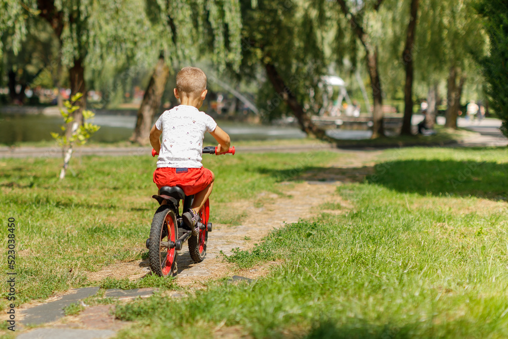 little boy riding a bike in a city park little boy riding a bike in a city park