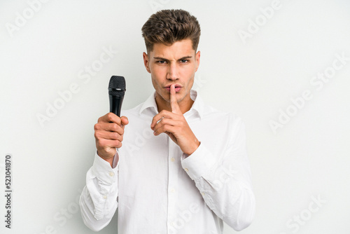 Young singer caucasian man isolated on white background keeping a secret or asking for silence.