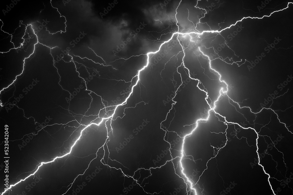 Fork lightning striking down during summer storm in black and white Fork lightning striking down during summer storm in black and white