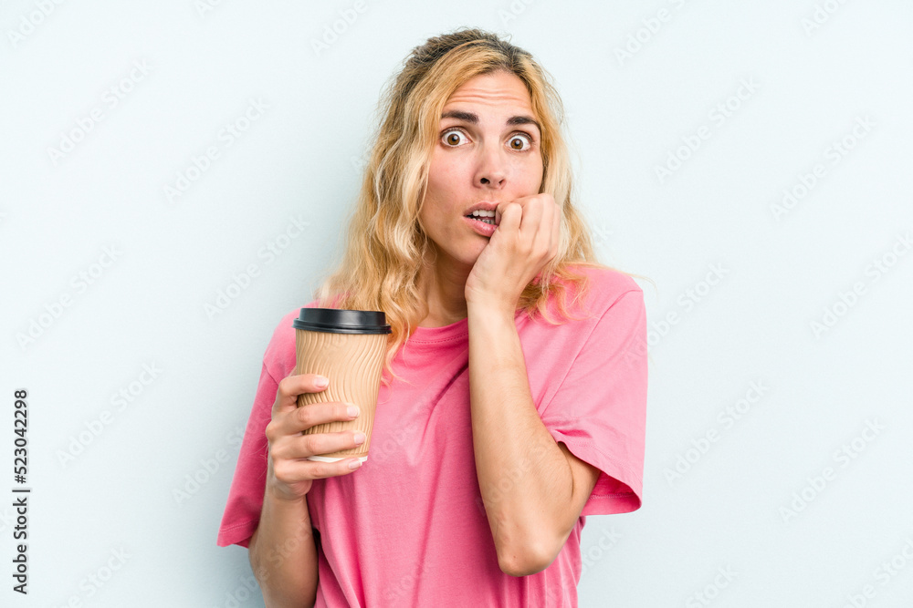 Young caucasian woman holding a take away coffee isolated on blue background biting fingernails, nervous and very anxious. Young caucasian woman holding a take away coffee isolated on blue background biting fingernails, nervous and very anxious.