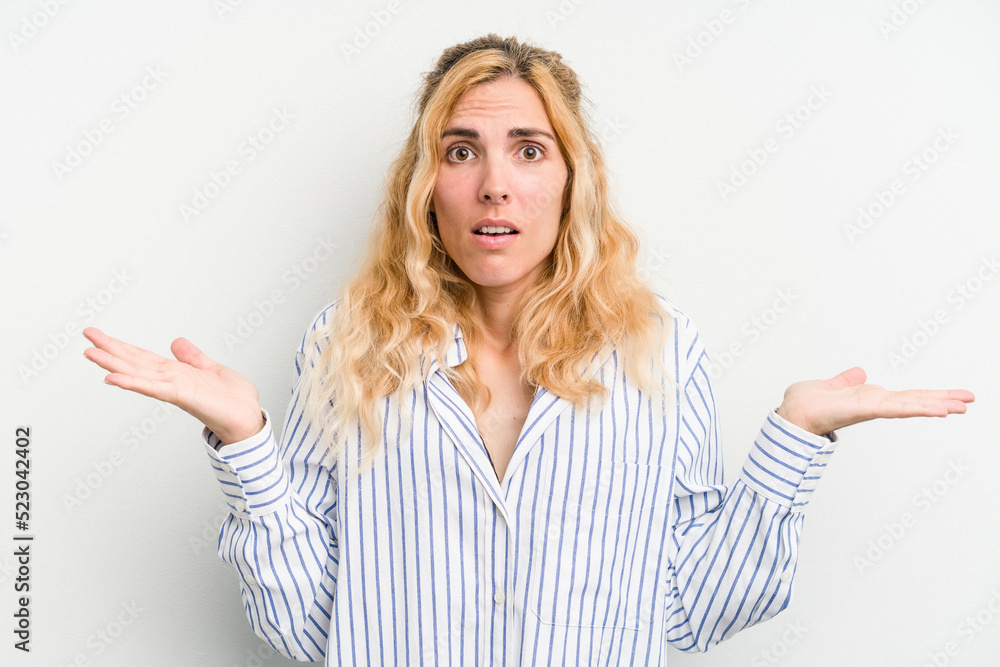 Young caucasian woman isolated on white background confused and doubtful shrugging shoulders to hold a copy space. Young caucasian woman isolated on white background confused and doubtful shrugging shoulders to hold a copy space.
