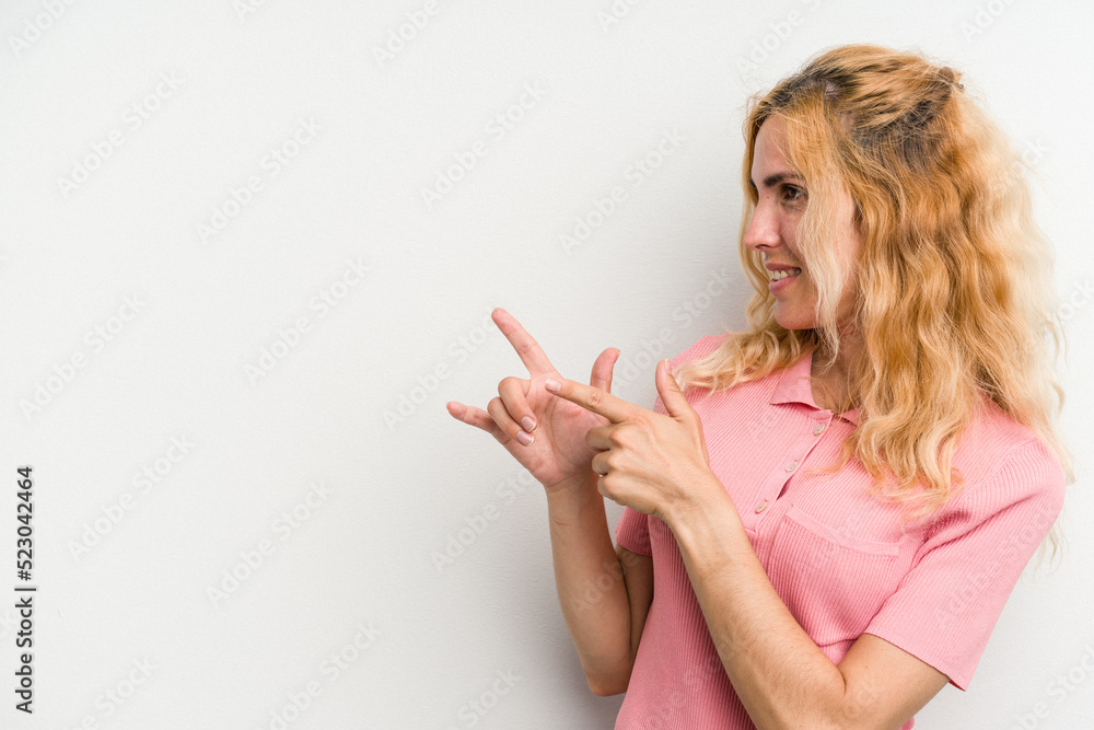 Young caucasian woman isolated on white background points with thumb finger away, laughing and carefree.