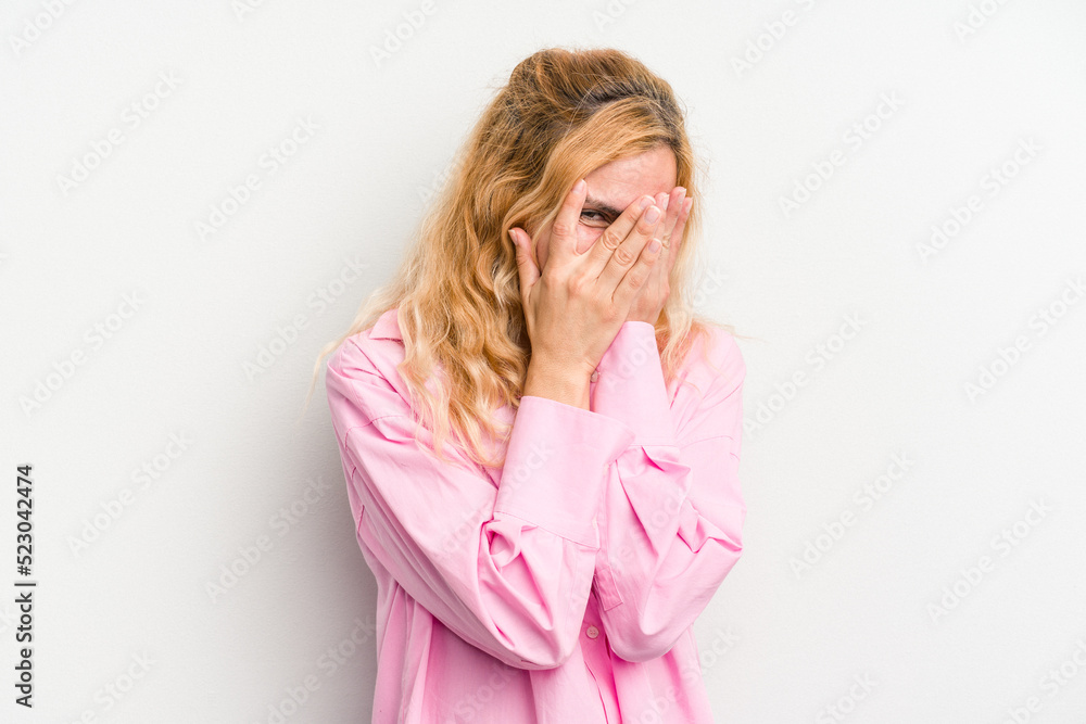 Young caucasian woman isolated on white background blink at the camera through fingers, embarrassed covering face. Young caucasian woman isolated on white background blink at the camera through fingers, embarrassed covering face.