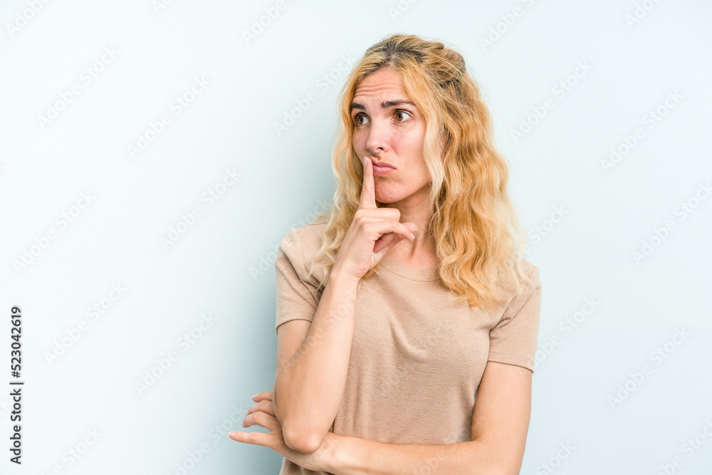 Young caucasian woman isolated on blue background keeping a secret or asking for silence. Young caucasian woman isolated on blue background keeping a secret or asking for silence.