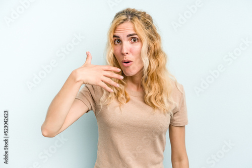 Young caucasian woman isolated on blue background laughing about something, covering mouth with hands.