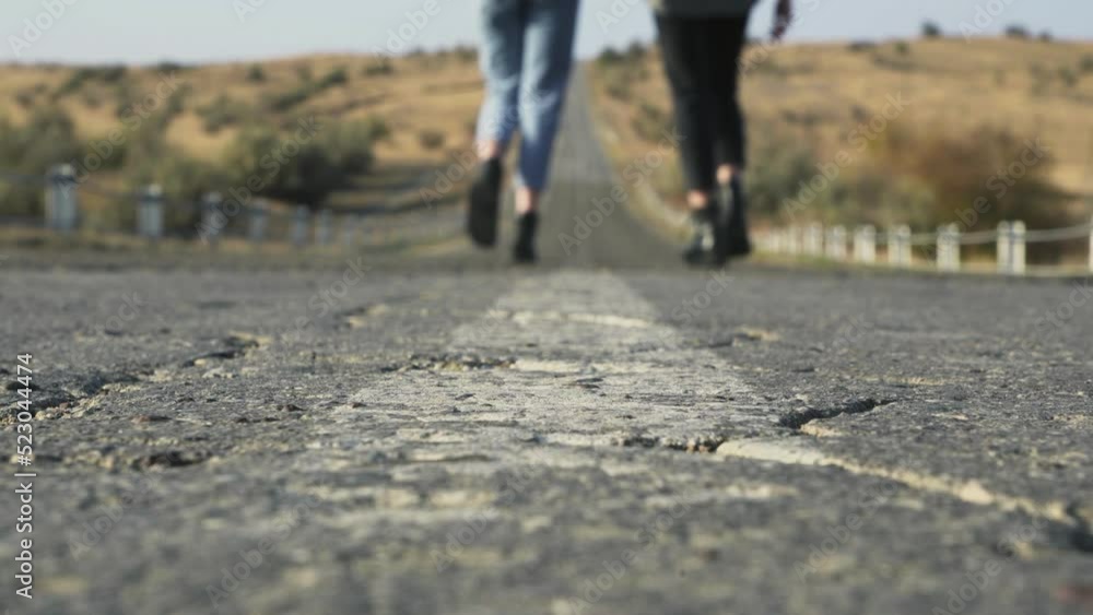 Clsoe up of feet on two women walks out of camera on country road Clsoe up of feet on two women walks out of camera on country road