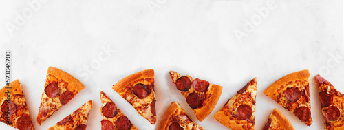 Pepperoni pizza slice top border. Overhead view on a white marble banner background. Copy space.
