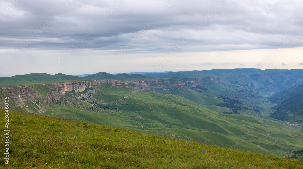 Beautiful landscape - panoramic view of green mountains and hills blurred in morning haze from bermamyt plateau in karachay-cherkessia Russia and dramatic clouds and copy space