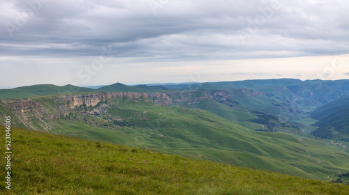 Beautiful landscape - panoramic view of green mountains and hills blurred in morning haze from bermamyt plateau in karachay-cherkessia Russia and dramatic clouds and copy space