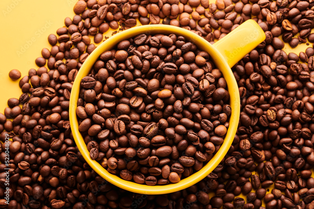 Cup of freshly brewed roasted coffee beans on yellow background Cup of freshly brewed roasted coffee beans on yellow background