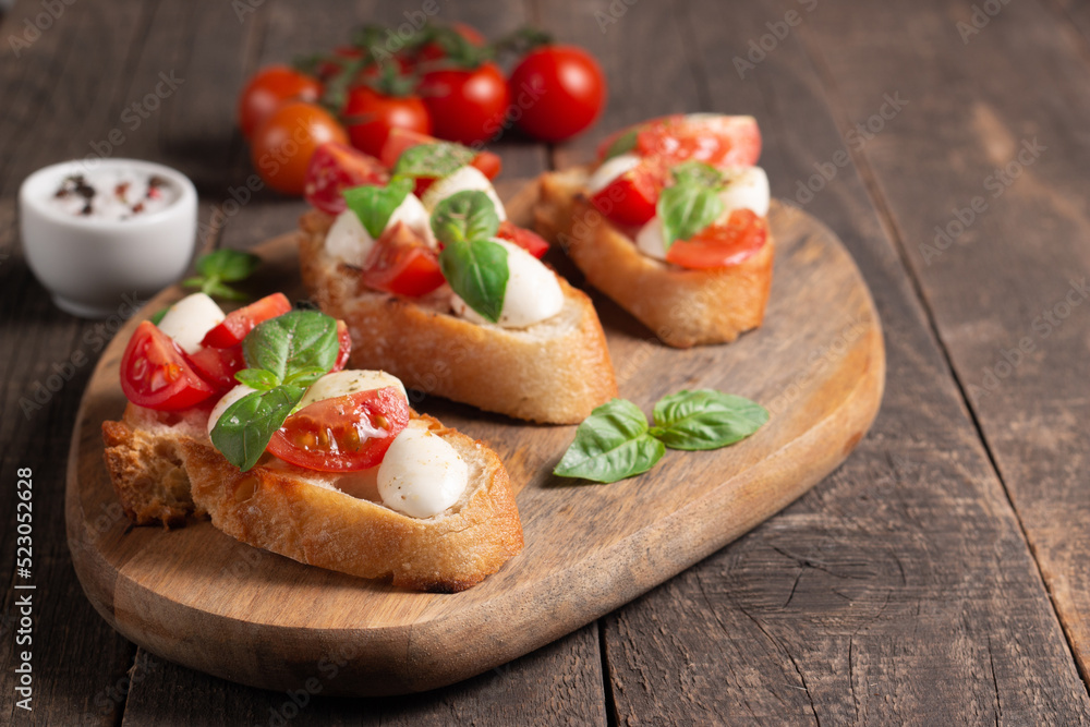 Tomato, basil and cheese fresh made caprese bruschetta. Italian tapas, antipasti with vegetables, herbs and oil on grilled ciabatta and baguette bread. Sandwich.
