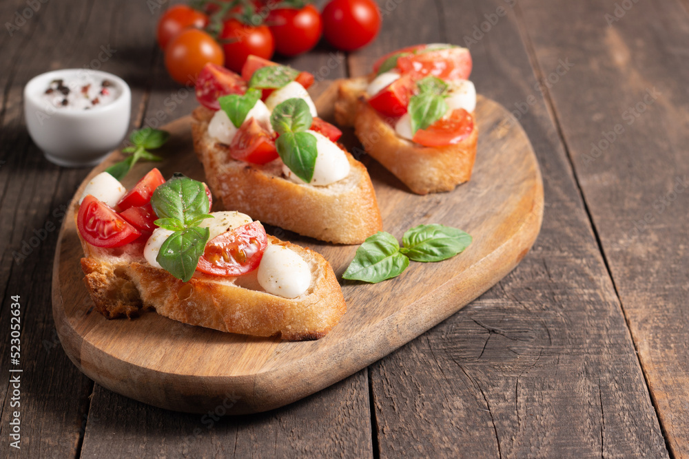 Tomato, basil and cheese fresh made caprese bruschetta. Italian tapas, antipasti with vegetables, herbs and oil on grilled ciabatta and baguette bread. Sandwich.