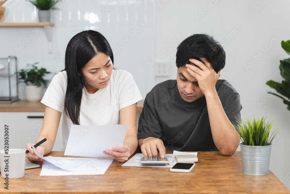 Stressed Asian couple looking at financial debt notice papers from bank. Stressed Asian couple looking at financial debt notice papers from bank.