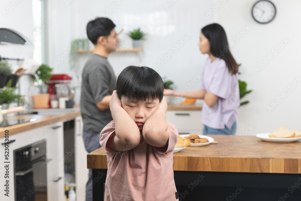 domestic violence. Stressed Asian kid covering his face after mom and dad started arguing.
