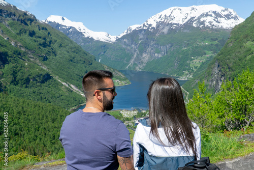 Couple in love looking at each other with the Geirangerfjord in the background on a sunny day.
