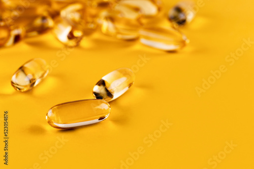 A bunch of Omega 3 capsules on a yellow background. Close up, top view, high resolution product. Copy space.