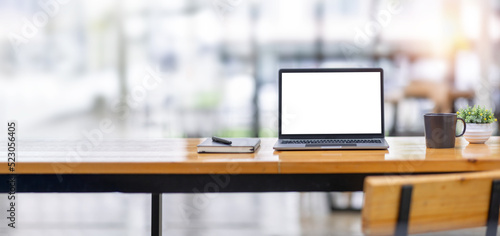 Laptop screen, Laptop Computer, notebook copy space, and eyeglasses sitting on a desk in a large open plan office space after working hours 