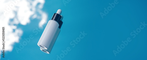 Cosmetic background, white Bottle with a pipette on a blue sky background