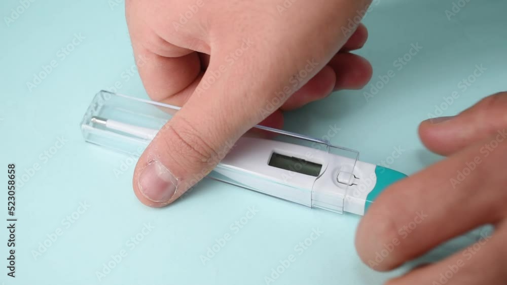 Hand taking a white digital thermometer on blue background Hand taking a white digital thermometer on blue background