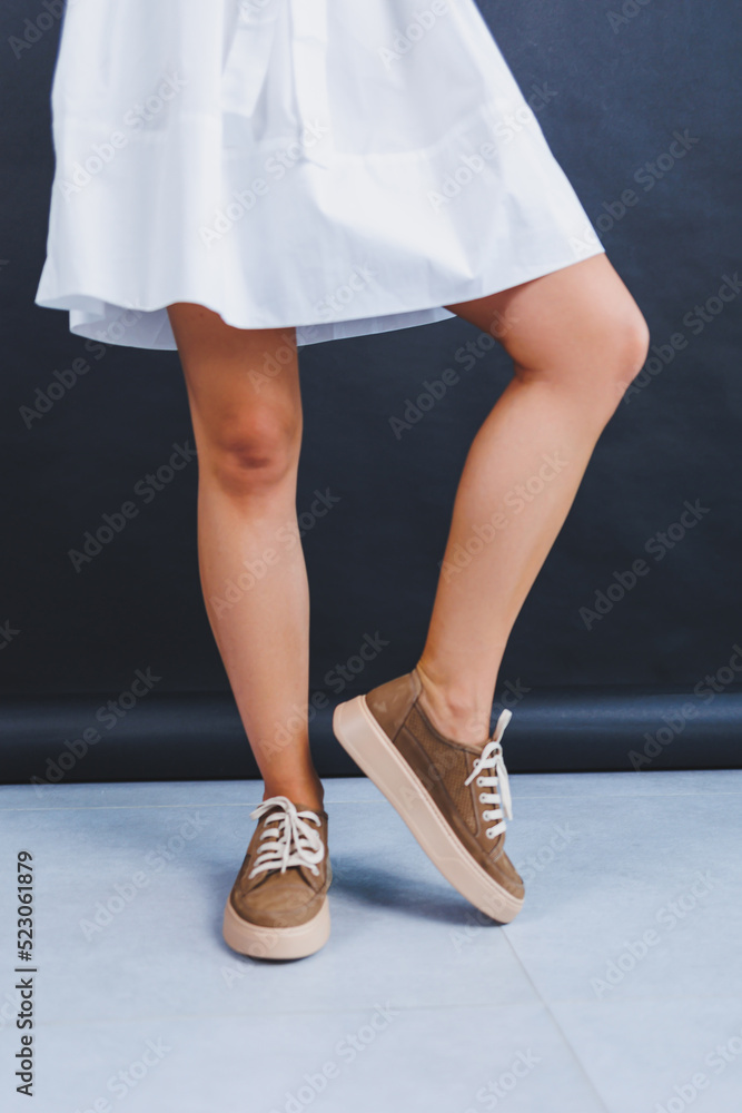 Women's brown leather sneakers on the legs close-up. Collection of summer women's shoes
