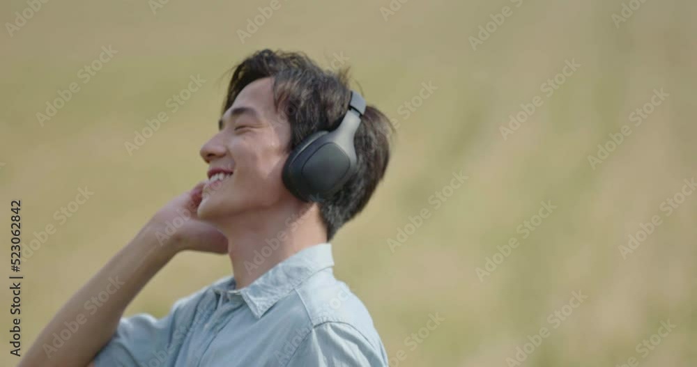 Happy young man wearing headphones in wheat field,4K Happy young man wearing headphones in wheat field,4K