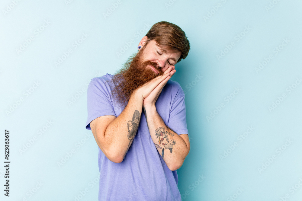 Young caucasian red-haired man isolated on blue background yawning showing a tired gesture covering mouth with hand. Young caucasian red-haired man isolated on blue background yawning showing a tired gesture covering mouth with hand.