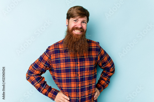 Young caucasian red-haired man isolated on blue background happy, smiling and cheerful.