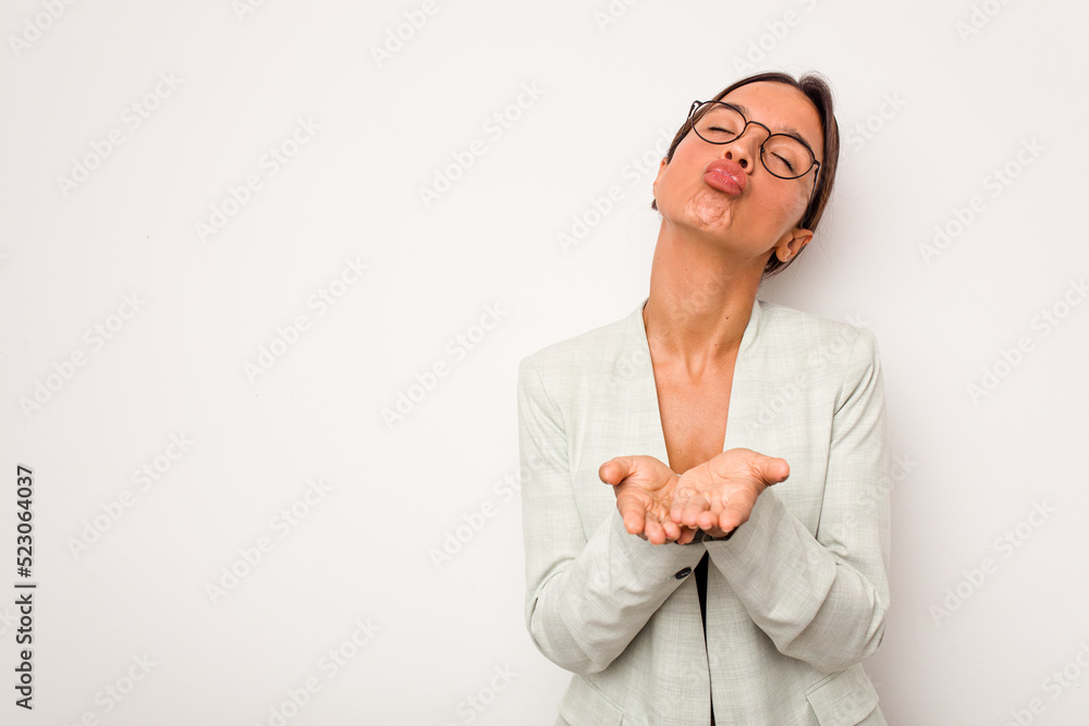 Young hispanic woman isolated on white background folding lips and holding palms to send air kiss. Young hispanic woman isolated on white background folding lips and holding palms to send air kiss.